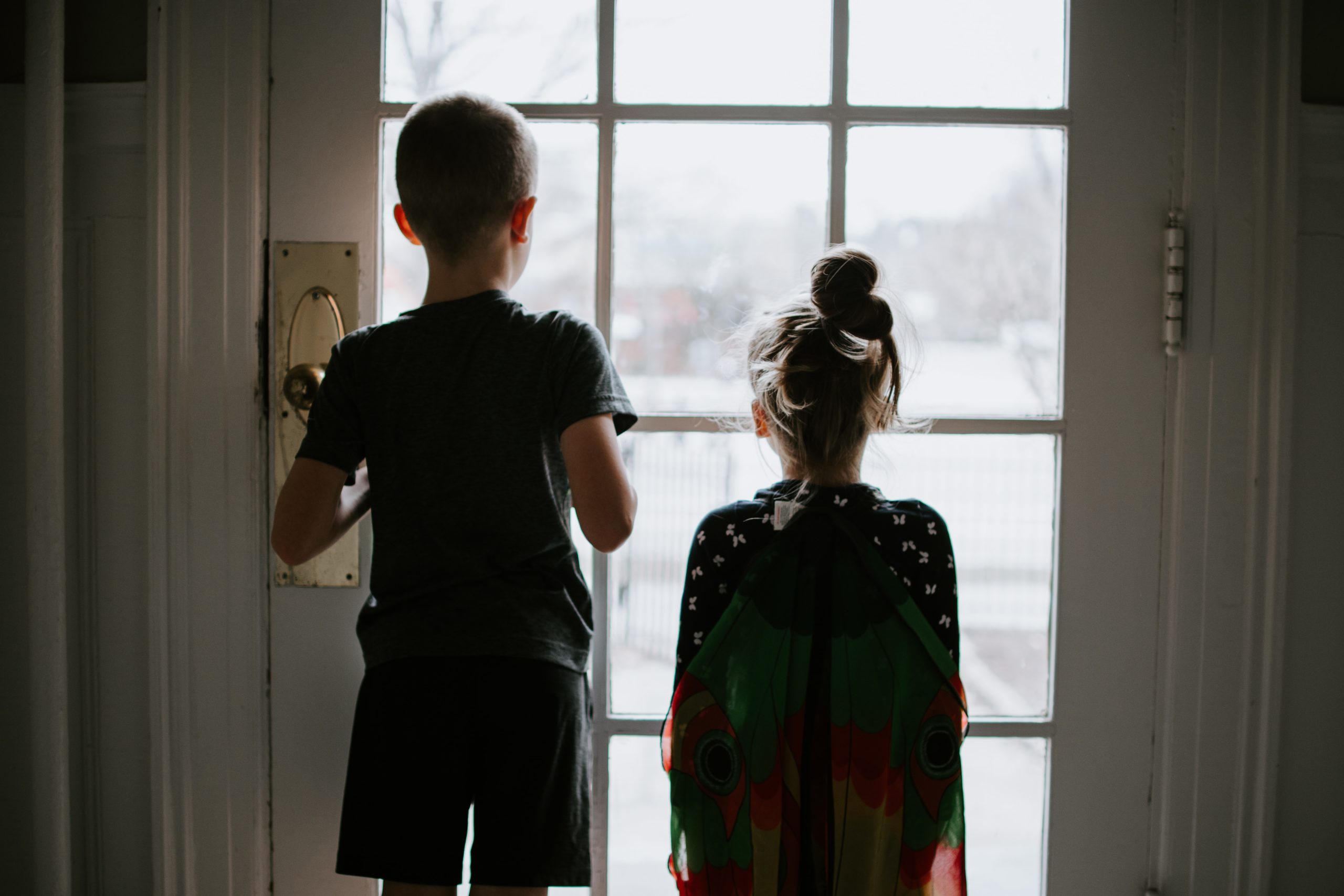 kids looking out door from covid quarantine
