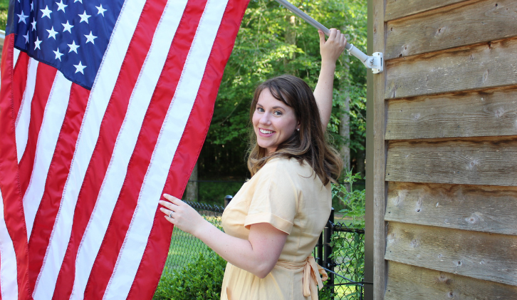 woman hanging American flag outside home