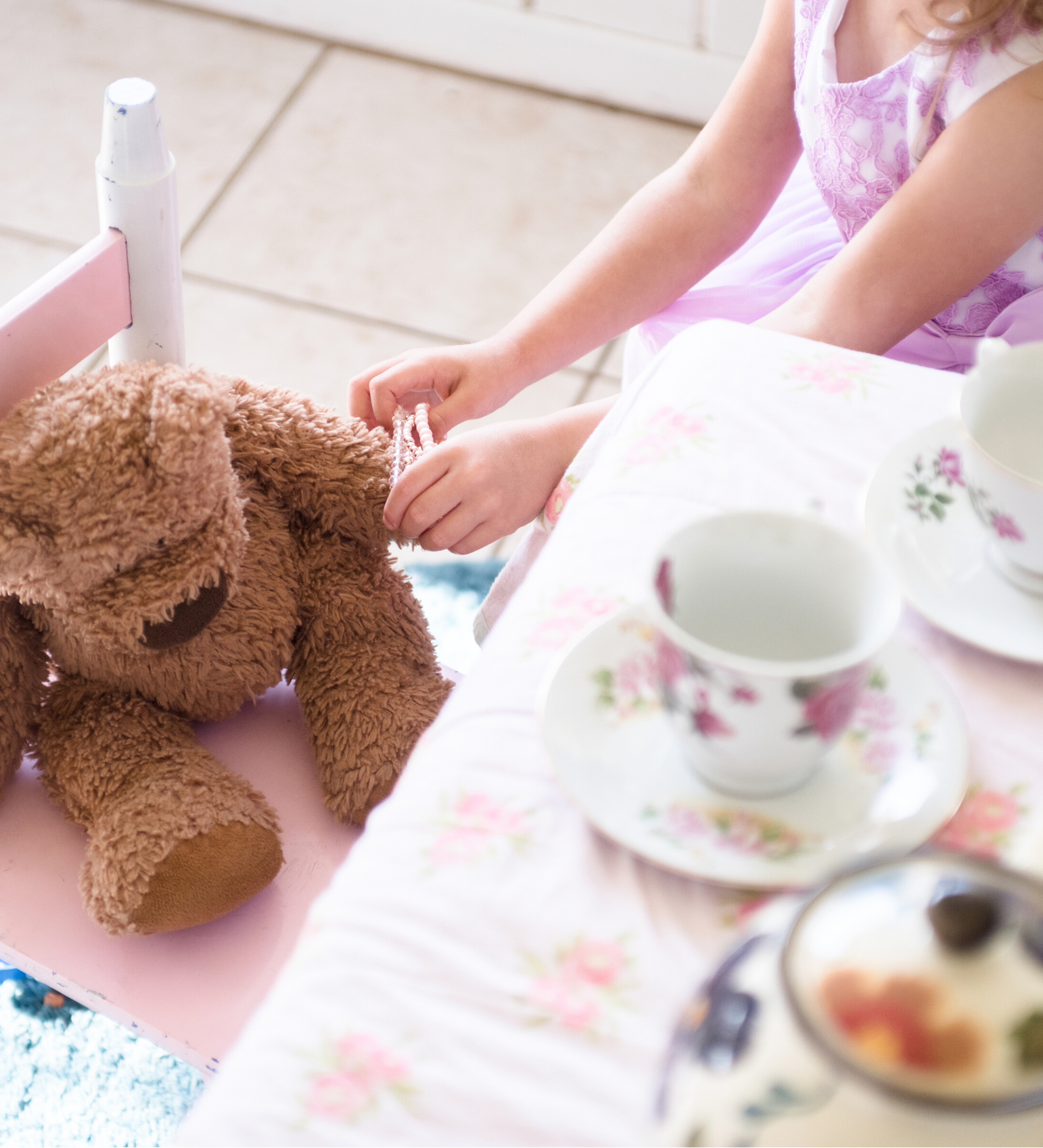 child having a tea party with a teddy bear